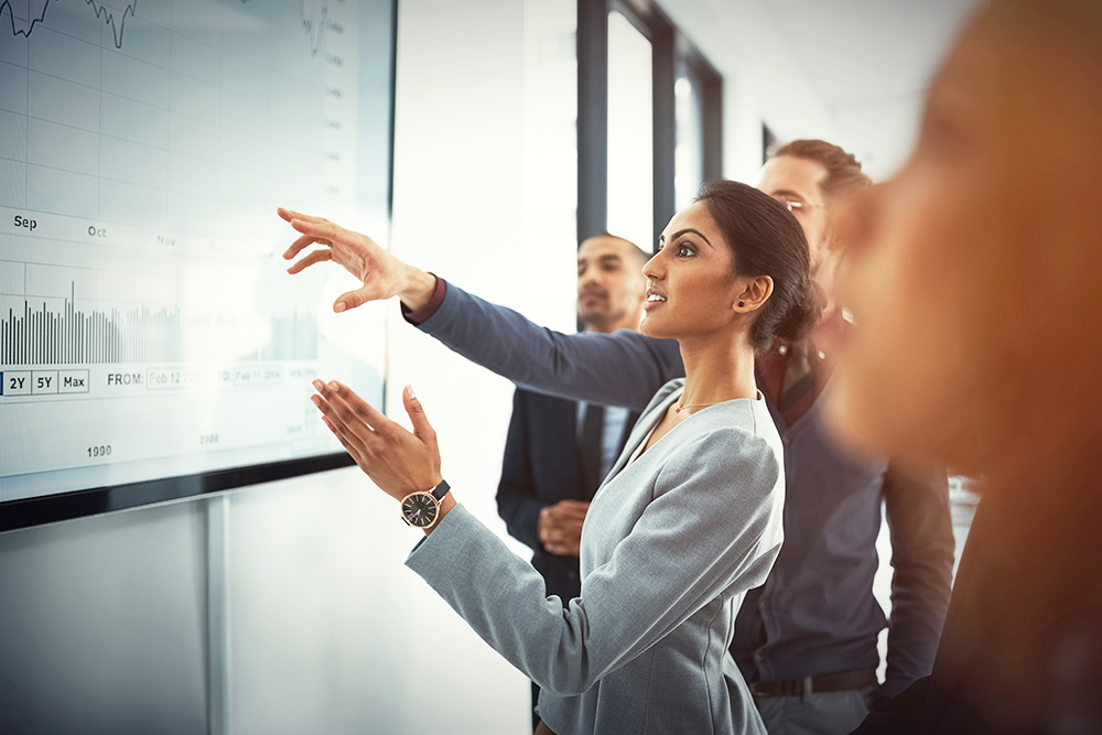 woman-pointing-to-white-board-with-group